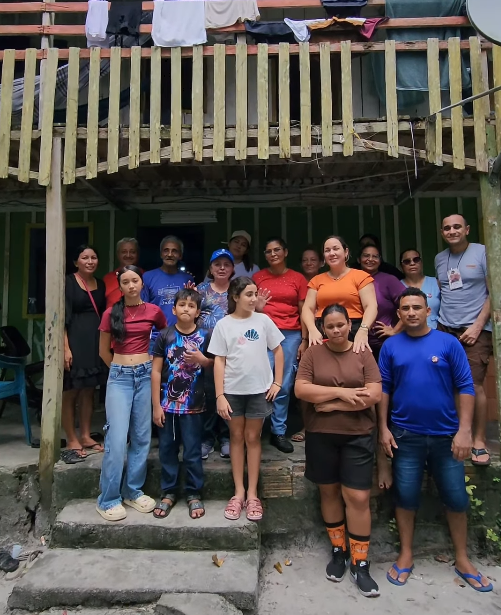 Comunidade amazônica reunida em frente à casa de madeira